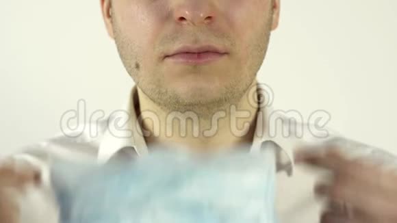 一个男人把一个防护的医疗面具戴在脸上以抵御病毒预防冠状病毒大流行的概念视频的预览图