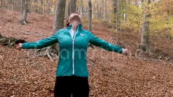 秋天的早晨一位运动的年轻女子举起双手在山上享受大自然视频的预览图