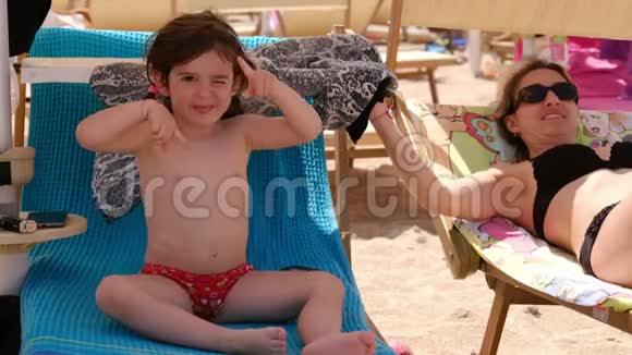 有趣的女婴在暑假期间和孩子们一起在沙滩椅上跳舞视频的预览图