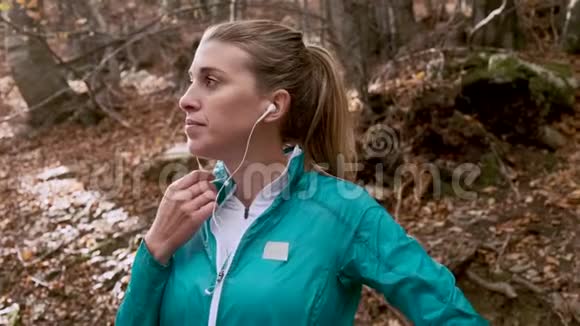 秋天的早晨在山上跑步后一位运动的年轻女子一边听音乐一边放松视频的预览图