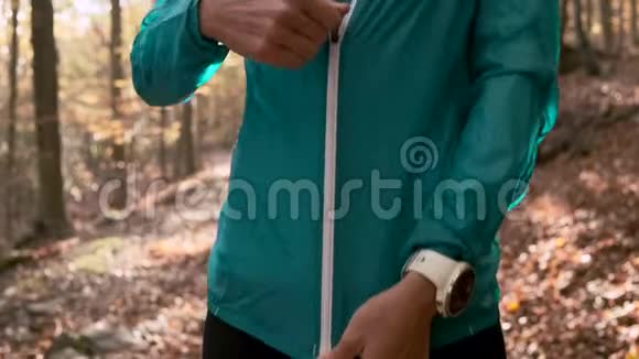 在秋天的早晨在山上跑步后一位运动的年轻女子正在拉链上夹克环顾四周视频的预览图
