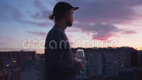 年轻人喝着酒看着城市的日落视频的预览图