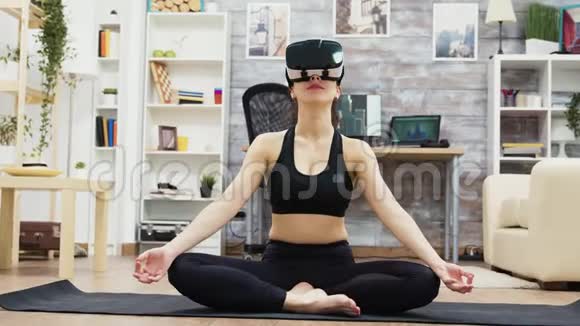 美丽的年轻女子戴着虚拟现实的眼镜做瑜伽视频的预览图