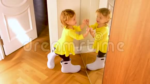 在家镜子附近试着穿成人胶靴的可爱小女孩视频的预览图