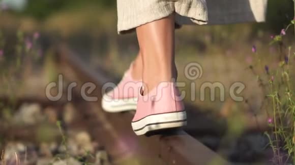 女孩沿着铁路走浪漫的慢动作追踪拍摄的年轻女孩双脚特写行走在铁路上视频的预览图