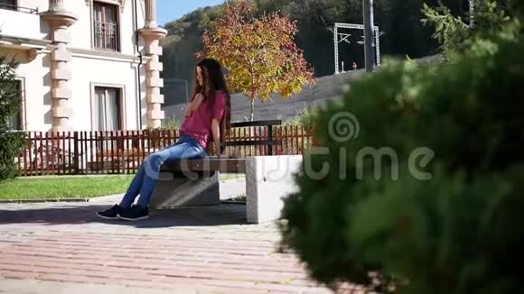 夏天独自坐在长凳上的年轻女子户外视频的预览图