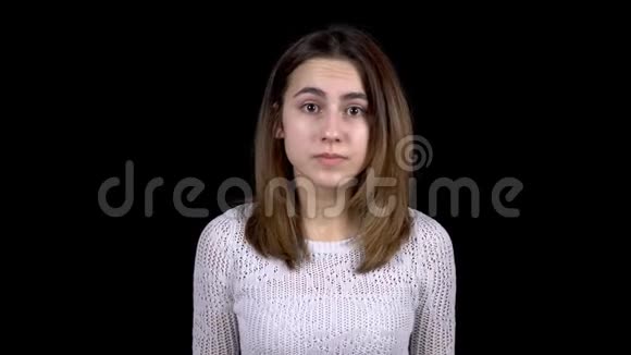 这位年轻女子脸上流露出恐惧的情绪一个女人吓得发抖在黑色的背景上环顾四周视频的预览图