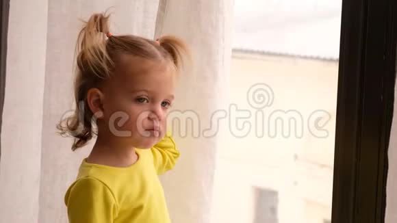 一个悲伤的小女孩在家的窗户附近做梦视频的预览图