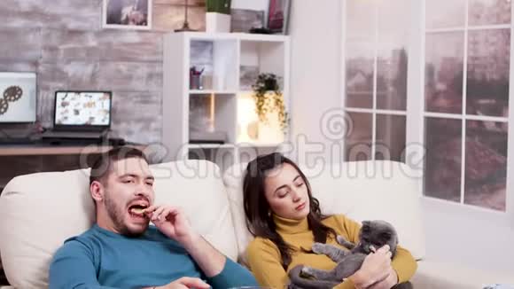 疲惫的男人用电视遥控器坐在沙发上视频的预览图