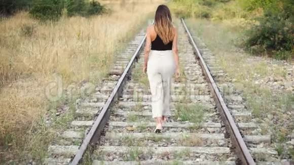 时髦的年轻女子走在铁轨上视频的预览图