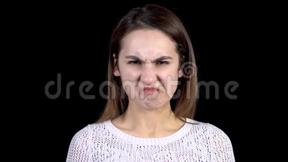 一个年轻的女人脸上流露出厌恶的情绪在黑色背景特写镜头上女人的脸因憎恶而扭曲视频的预览图