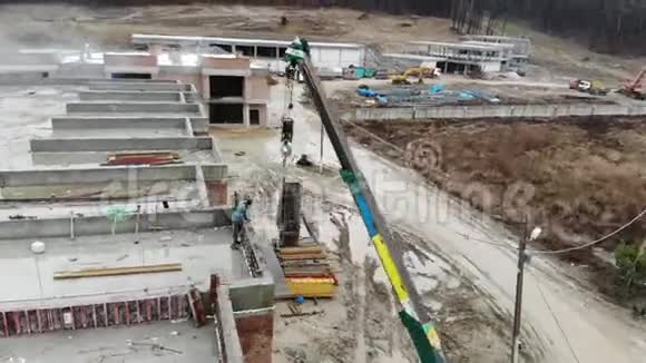 小型建筑起重机吊运重金属结构的鸟瞰图在建筑起重机周围飞行视频的预览图