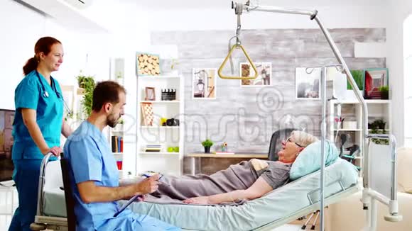 一组男女护士检查一位躺在病床上的老太太视频的预览图