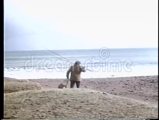带着钓鱼竿在沙滩上漫步的人的后景视频的预览图