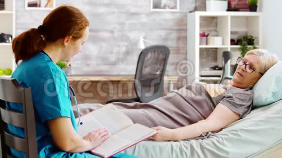 一位老太太躺在病床上一位护士正在给她看书视频的预览图