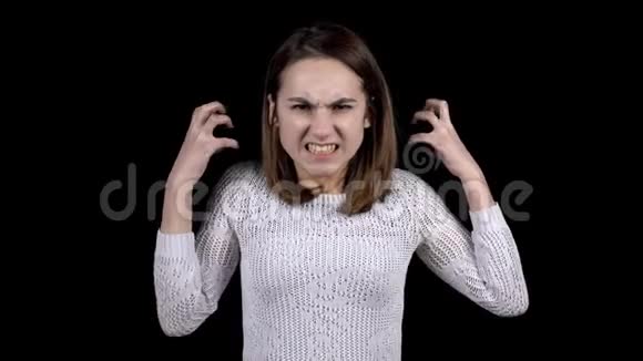 这位年轻女子脸上流露出愤怒的情绪女孩在黑色的背景上咬着牙皱着眉头视频的预览图