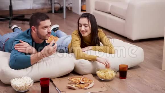 坐在地板上吃披萨和薯条的放松夫妇视频的预览图