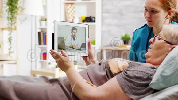 躺在病床上的老年残疾妇女与医生在线视频通话视频的预览图
