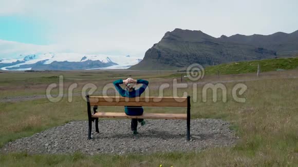 一个女人坐在长凳上钦佩冰岛的本性视频的预览图