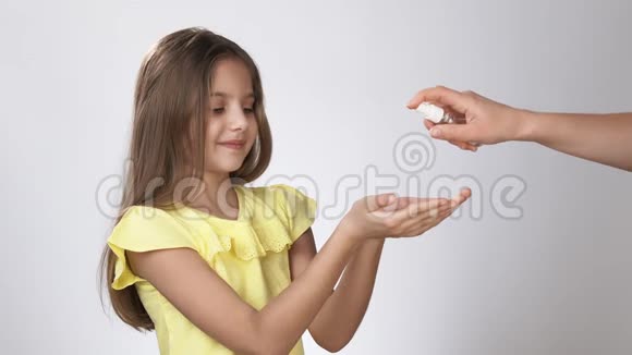 小孩子用防腐剂处理他们的手一个小女孩在她的手上喷洒了一种防腐剂视频的预览图