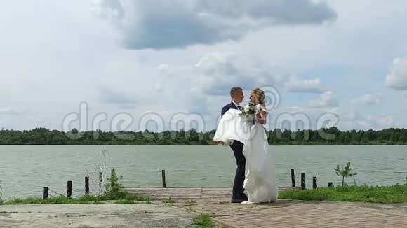 新郎把新娘抱在湖边码头上复制空间视频的预览图
