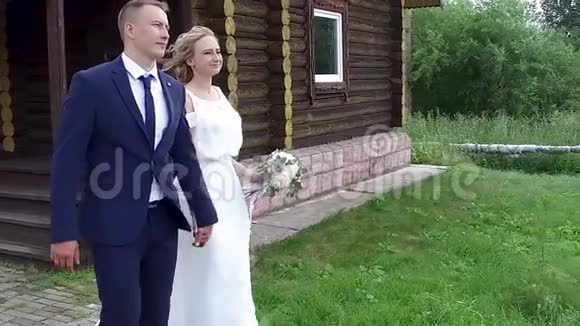 美丽的新婚新娘和新郎带着一束鲜花幸福地牵着手来到户外视频的预览图