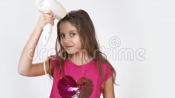 一个小女孩用吹风机擦干头发真诚地微笑视频的预览图