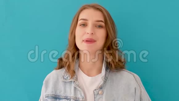 年轻女子对着镜头对着蓝色背景说话视频的预览图
