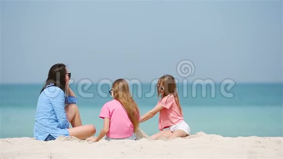 妈妈和小女儿在热带海滩上做沙堡视频的预览图