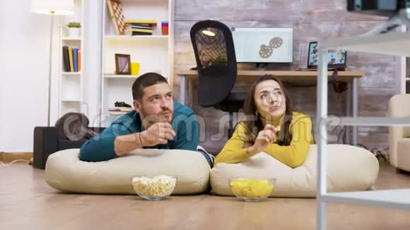 快乐的情侣坐在枕头上看电视视频的预览图