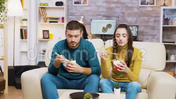 坐在沙发上用筷子吃面条的夫妇视频的预览图