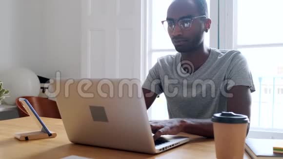 年轻的黑人商人在办公室里用笔记本电脑工作视频的预览图