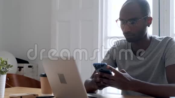 黑人年轻的商人在办公室里用智能手机和喝咖啡视频的预览图