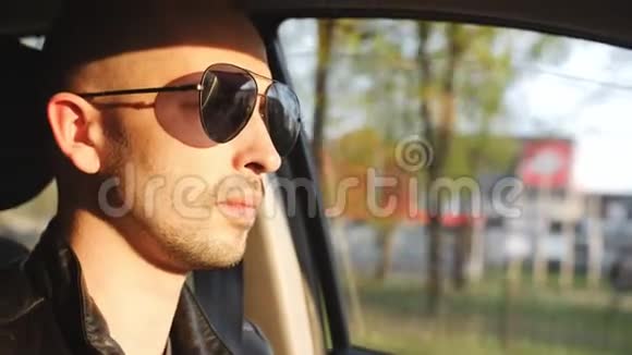 日落时戴太阳镜的人坐在车里开车视频的预览图