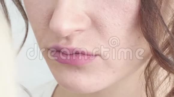 化妆师的手把化妆涂在一个年轻女人的脸上女孩在专业沙龙做唇妆晚上视频的预览图