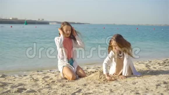 两个快乐的小女孩在热带海滩玩得很开心视频的预览图
