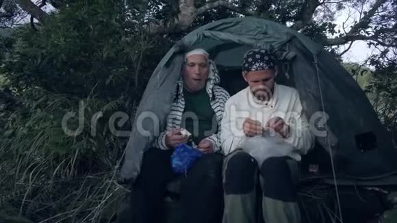 旅行者晚上在森林露营的帐篷里吃晚饭视频的预览图