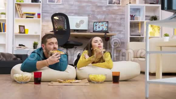 快乐的白种人夫妇坐在枕头上吃披萨视频的预览图
