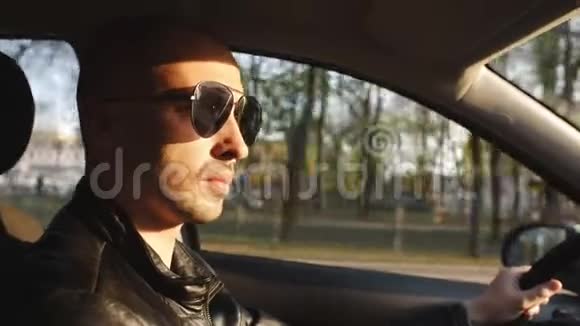 日落时戴太阳镜的人坐在车里开车视频的预览图