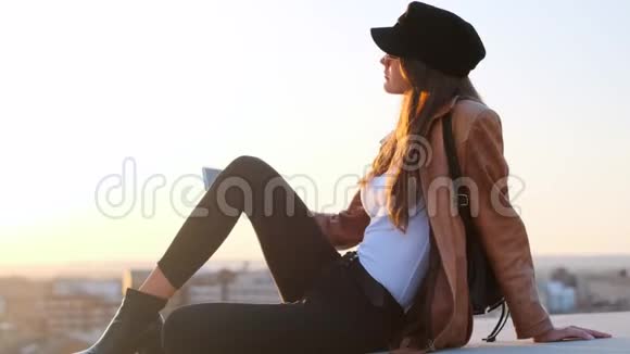 漂亮的年轻女人坐在屋顶上用手机自拍视频的预览图