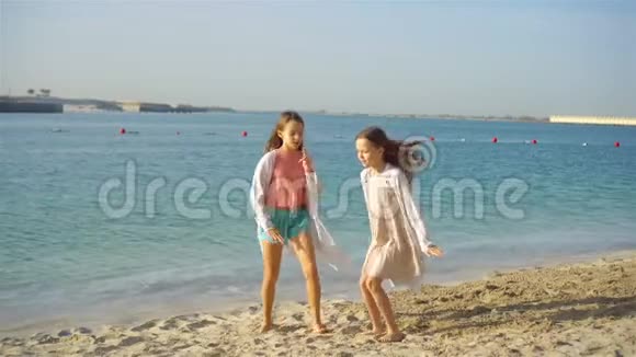 小快乐有趣的女孩在热带海滩玩得很开心阳光明媚的一天大海里有雨视频的预览图