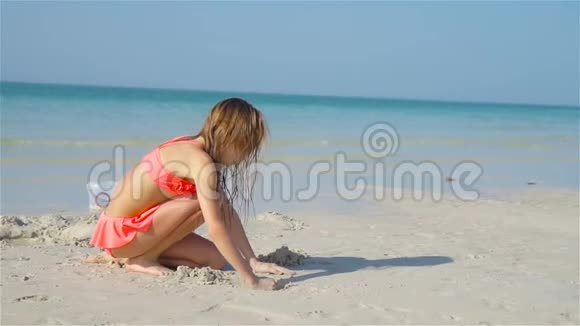 可爱的小女孩在白色的海滩上玩海滩玩具视频的预览图