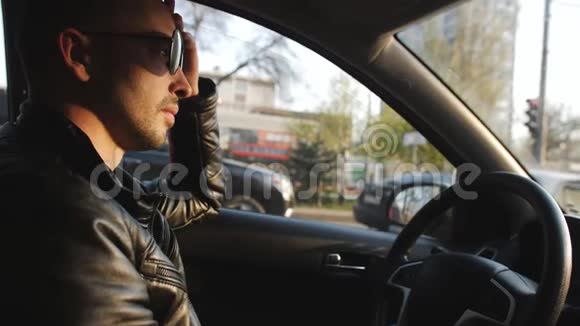 日落时分一个戴墨镜的人在汽车上行驶在城市交通中视频的预览图
