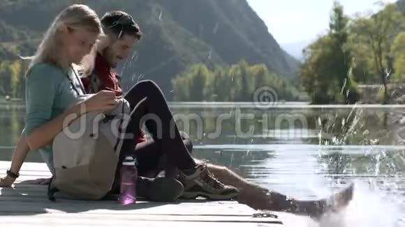 两个旅行徒步旅行者在山湖里玩水时在爱中享受大自然视频的预览图