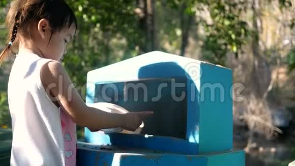 可爱的小女孩在公共公园的回收箱里扔塑料食品容器拯救世界的概念零浪费视频的预览图