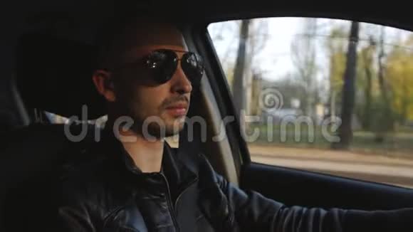 一个穿着皮夹克和太阳镜坐在车里的人视频的预览图
