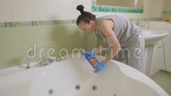 戴手套的女人彻底清洗浴室里的按摩浴缸视频的预览图