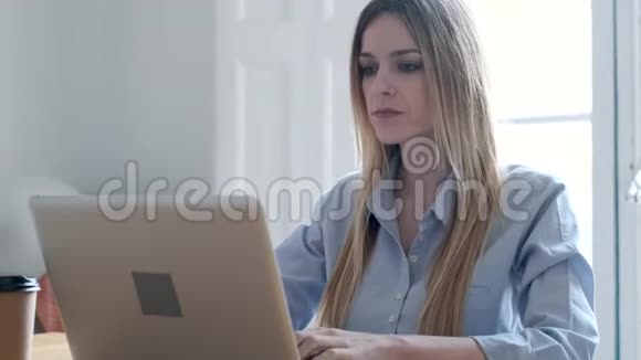 集中精力在办公室的办公桌上用笔记本电脑工作的年轻商务女性视频的预览图