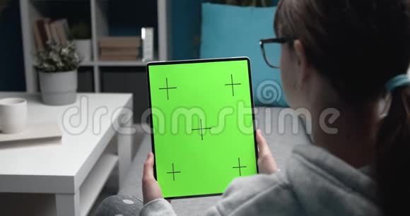 年轻女孩看着绿色的数字平板电脑屏幕视频的预览图