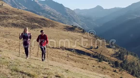 两个徒步旅行者带着背包步行同时看着山上的风景视频的预览图